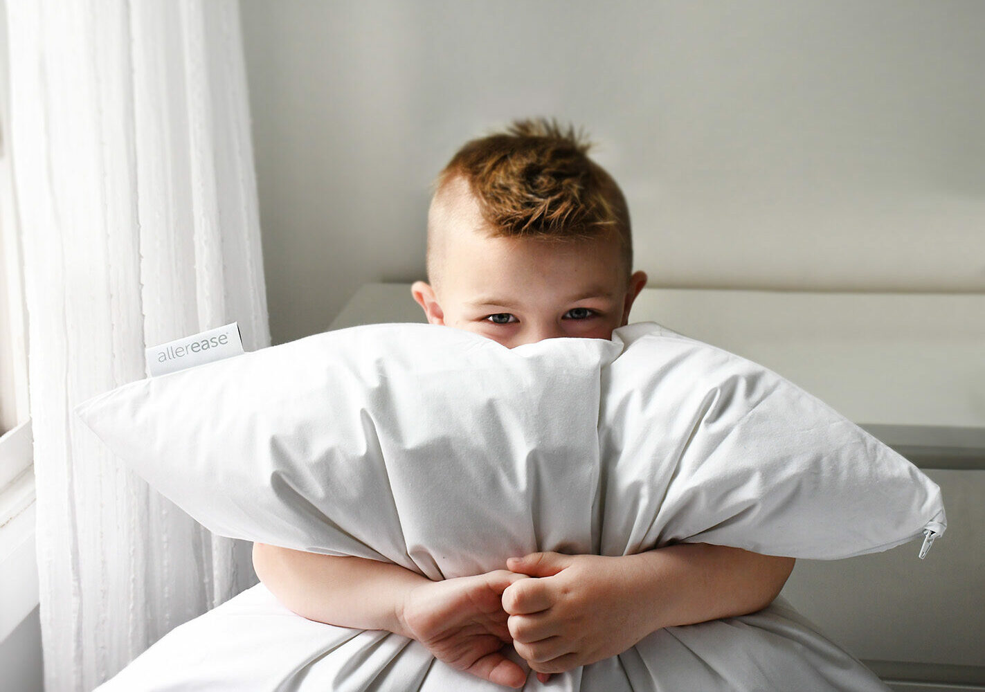A little boy hugging a pillow.