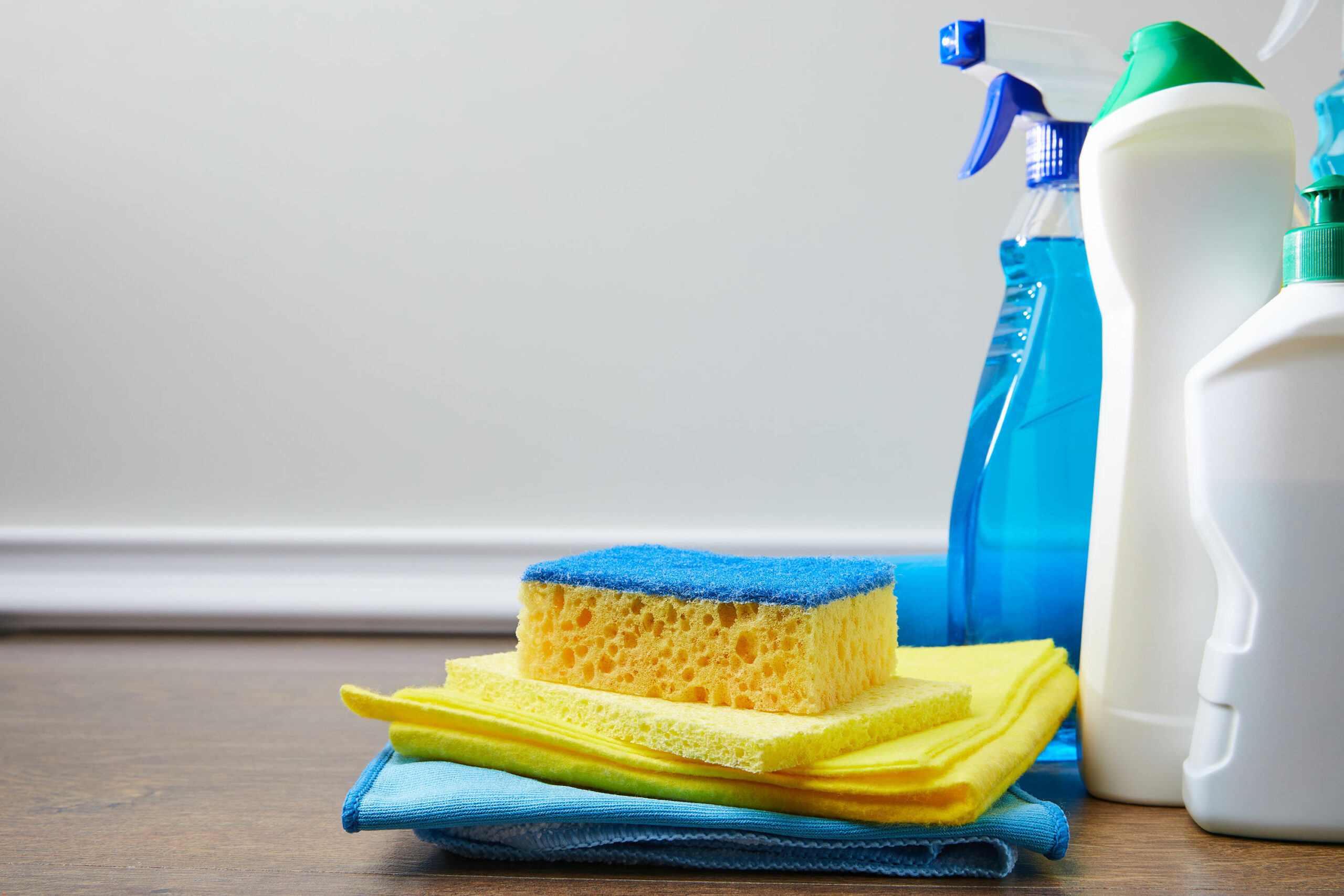 Blue and yellow sponge rags and bottles for spring cleaning
